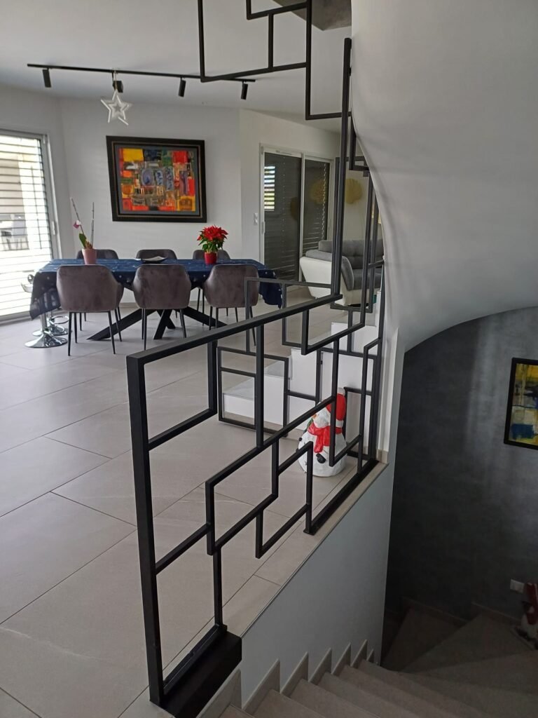 Claustra / garde-corps métal design géométrique séparant l'escalier et la salle à manger, réalisé sur mesure par Serrurier Express H24 à Uffholtz (Haut-Rhin). Fabrication de claustras métal, cloisons décoratives et métallerie d'intérieur sur mesure à Uffholtz, Cernay, Thann, Mulhouse et le Haut-Rhin. Tél : 0643188479 - 7 rue de Zaporojie 90000 Belfort / 20 rue d'Agen 68000 Colmar