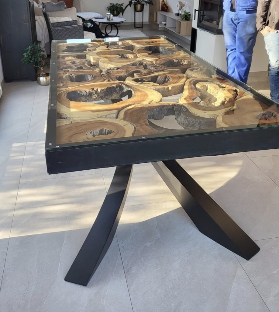Table sur mesure bois, métal et verre, design et originale, réalisée par Serrurier Express H24 à Thann (Haut-Rhin). Plateau en bois massif brut sculpté avec effet cascade, intégré sous verre, piètement métal noir sur mesure. Création de mobilier bois métal verre, métallerie et menuiserie d'art à Thann, Mulhouse, Colmar, Belfort et le Territoire de Belfort. Tél : 0643188479 - 7 rue de Zaporojie 90000 Belfort / 20 rue d'Agen 68000 Colmar